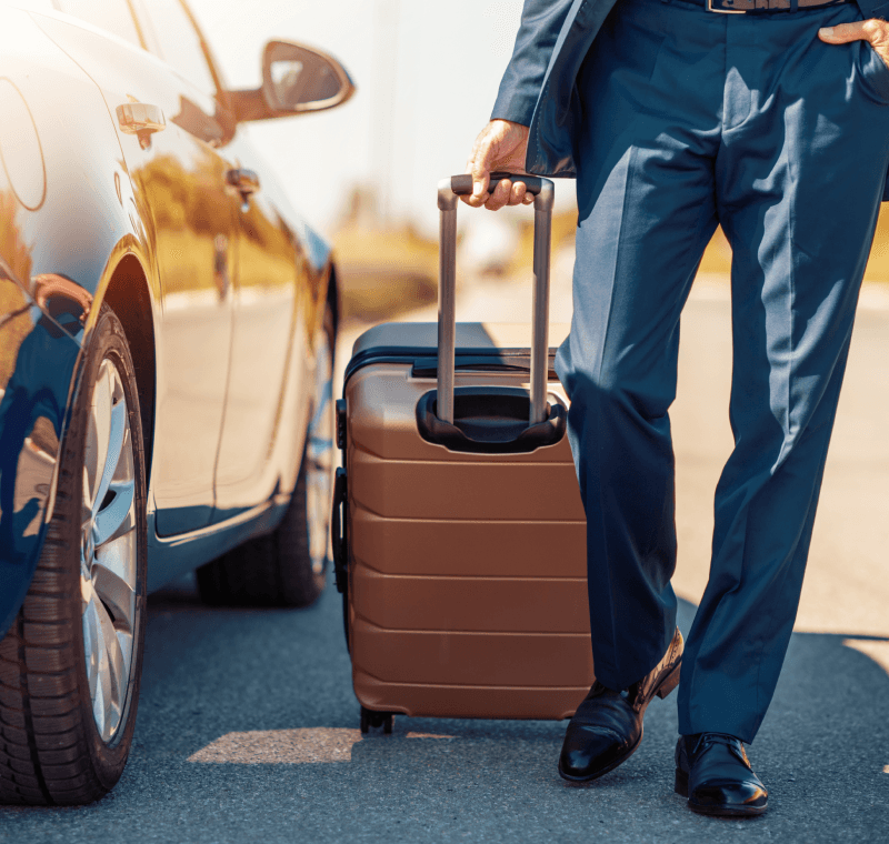 A man holding a suitcase standing next to a rental car, showing our case study of rent a car direct integration automation with rentalcars.com