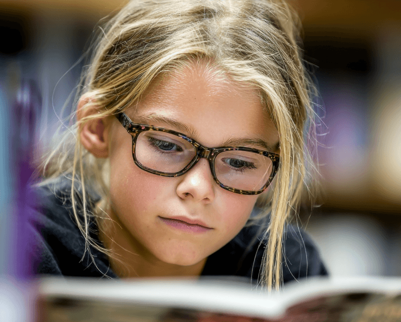 focused child sitting at a table, open book, learning, illustrating the idea behind mindeasy, an edtech & neurotechnology startup case study by mobitouch