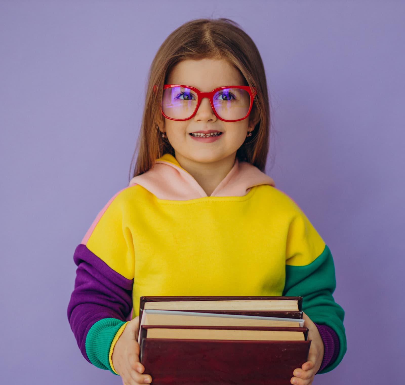 Smiling little girl in red glasses holding a stack of books